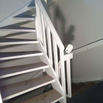 Ferdigstilt trapp som er malt i hvitt og med matte treplater som trinn