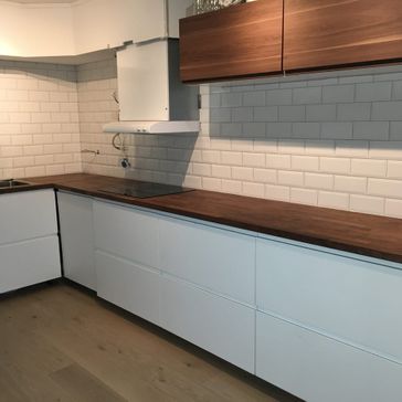 Ferdigstilt kjøkken med hvite fliser på veggen og nydelig mørk tre-benk