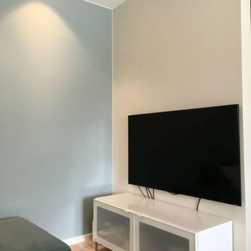 Lyseblå vegg med sofa og tv på hvit tv-benk