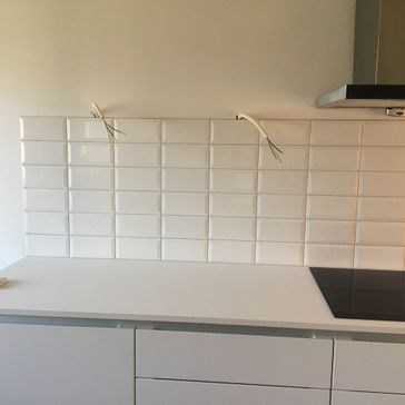 Legging av hvite fliser på over kjøkkenbenk