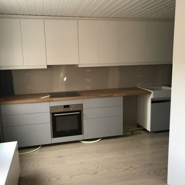 Oppusset kjøkken med benkeplate av tre, grå skuffer og hvite hyller