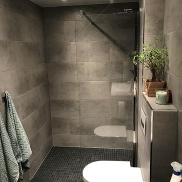 Ferdigstilt bad med brune sten-fliser, servant, toalett og dusj
