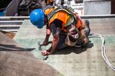 Arbeidskar med blå hjelm som slår ned spiker med hammer